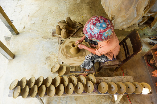 Hoi An, Vietnam - Mar 10, 2020: A woman is making a clay product on the pottery wheel in Thanh Ha pottery village.