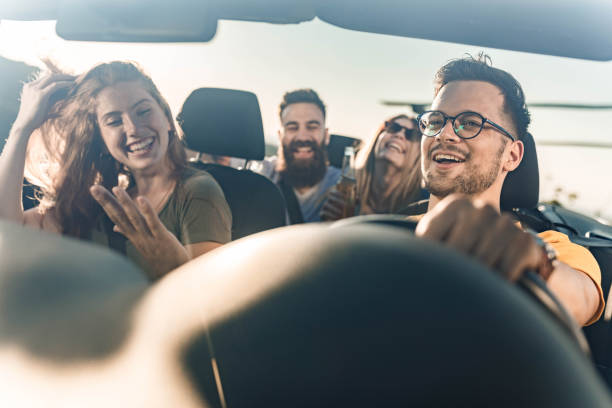 Young happy friends enjoying while going on their vacation by convertible car.