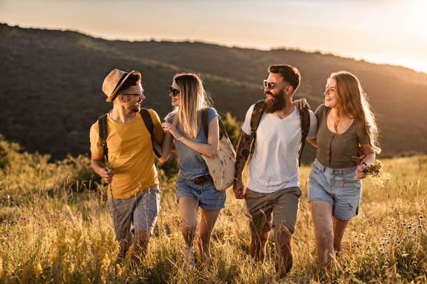 istock Young happy couples talking while walking in a meadow at sunset. 1396793330