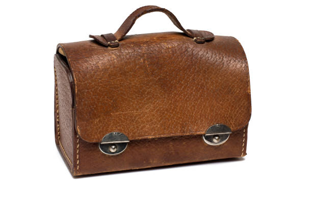 Close up of an old heavily used vintage retro small brown leather handbag doctor bag schoolbag with handle and metal fasteners on white background