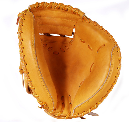 Shot of a baseball mitt and ball lying on the pitch during the day