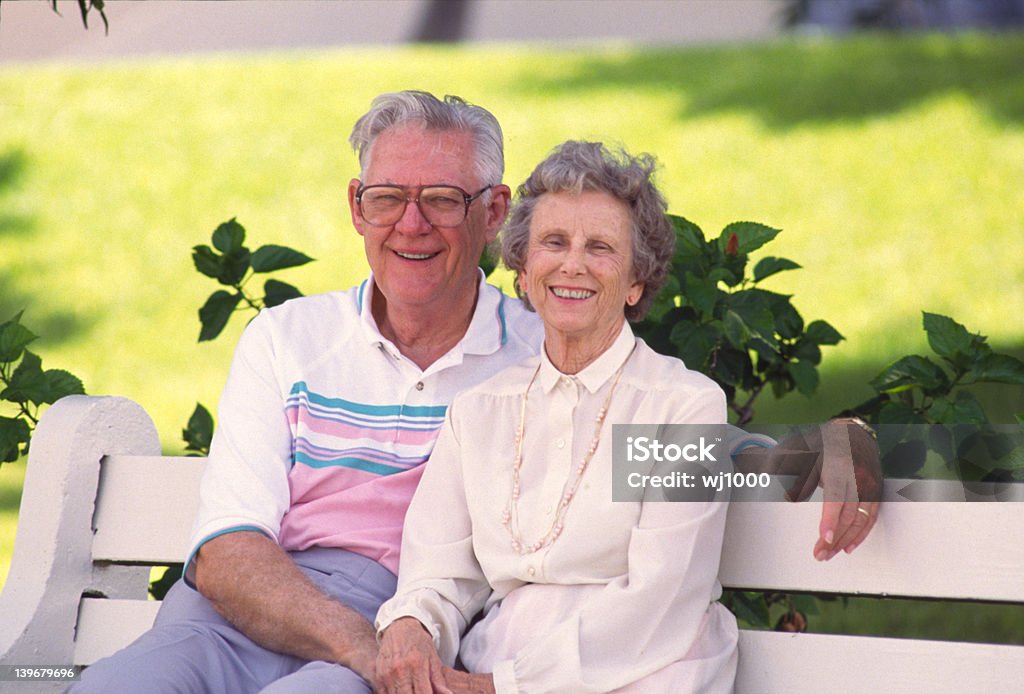 Coppia di pensionati seduti sulla panca - Foto stock royalty-free di Adulto