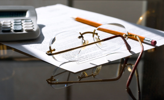 counting tax returns ( form calculator glasses pensil on a glass table in the morning light)