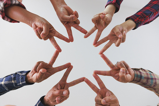 A diverse group of people connects their hands as a supportive sign expressing a sense of teamwork. Unity and togetherness.