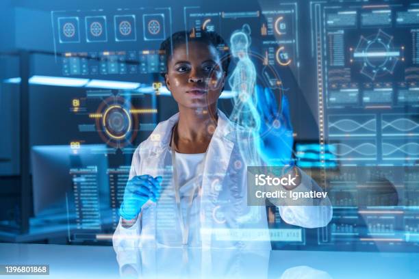 A Young African American Doctor Works On Hud Or Graphic Display In Front Of Her Stock Photo - Download Image Now