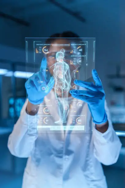 A small HUD or graphic display with a human body image and a scientist or a doctor, working with it, we see her behind the HUD in a modern laboratory with dark illumination