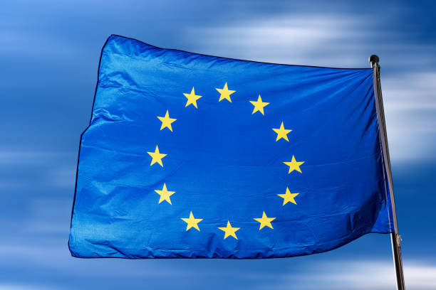 istock European Union Flag Waving in a Blue Sky with Clouds 1396802258