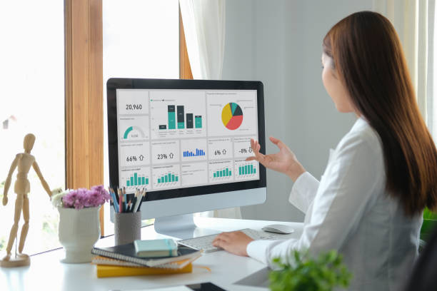 istock Rear view businesswoman analysing financial graph on computer at modern workplace. 1396803186