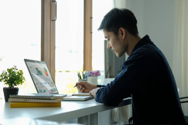 istock Side view focused young businessman analysing financial data on laptop computer. 1396806452
