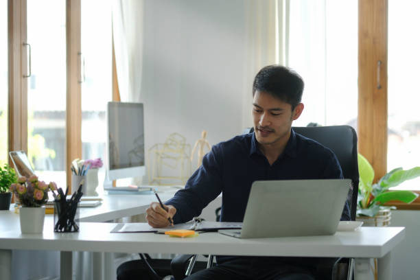 istock Handsome young businesspeople working with laptop computer and writing new idea on notebook. 1396806507