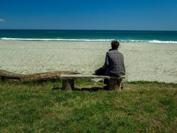 istock Lonely Senior Woman Sitting On The Beach 1396807771