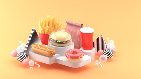 Hamburgers, hot dogs, donuts, french fries and soft drinks surrounded by colorful balls on an orange background.-3d rendering.