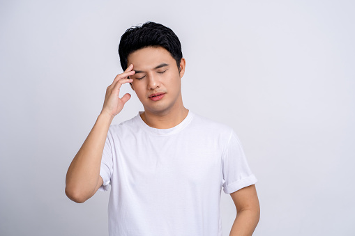 Young Asian man isolated on white background touching temples and having headache.