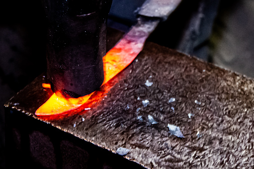 Blacksmith manually forging the molten metal