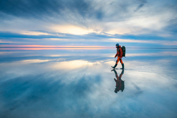istock Man traveler with backpack walking on the salt lake at sunset. 1396812212