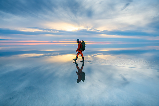 Man traveler walking on the lake at sunset.