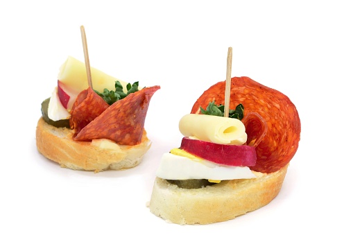 Two fresh salami cheese canapes on white background.