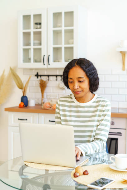 istock African-American female focused on remote work while sitting in kitchen and using laptop 1396814228