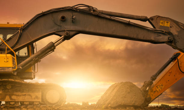Backhoe parked at construction site after digging soil. Bulldozer on sunset sky and clouds background. Digger after work. Earth moving machine at construction site at dusk. Digger with dirt bucket. retroexcavadora estacionada en el sitio de construcción después de cavar tierra. excavadora en el cielo al atardecer y nubes de fondo. excavadora después del trabajo. máquina de movimiento de tierras en el sitio de construcción al atardecer. excavador