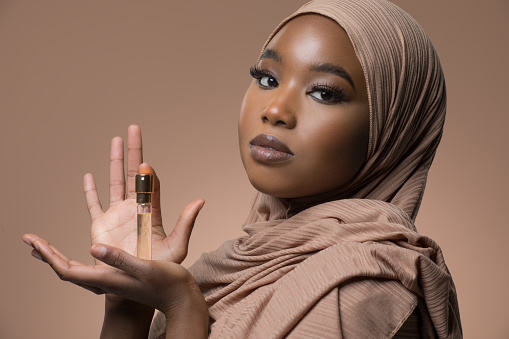 Beautiful Muslim Woman wearing hijab holding a perfume bottle
