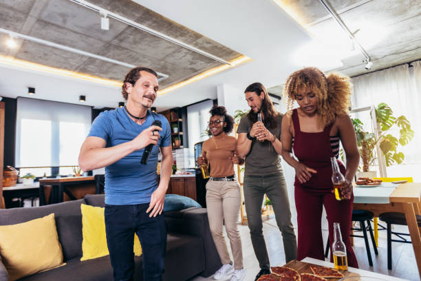 istock Group of young multicultural friends having party singing song using microphone at home. 1396819941