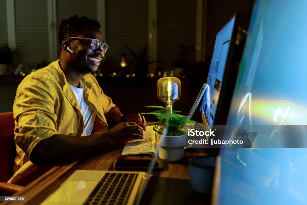 African man sitting at his desk and working on computer in office Business Stock Photo