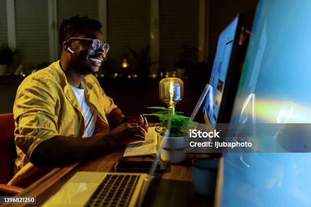 African Man Sitting At His Desk And Working On Computer In Office Stock Photo - Download Image Now