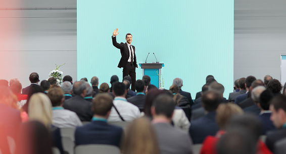 Business man making a speech in front of big audience