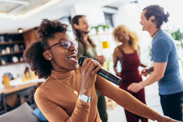 istock Group of young multicultural friends having party singing song using microphone at home. 1396821428