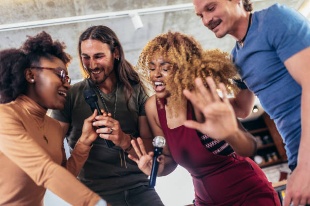 istock Group of young multicultural friends having party singing song using microphone at home. 1396821468