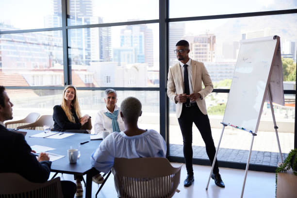istock Young businessman talking with coworkers during a whiteboard presentation in an office 1396824468