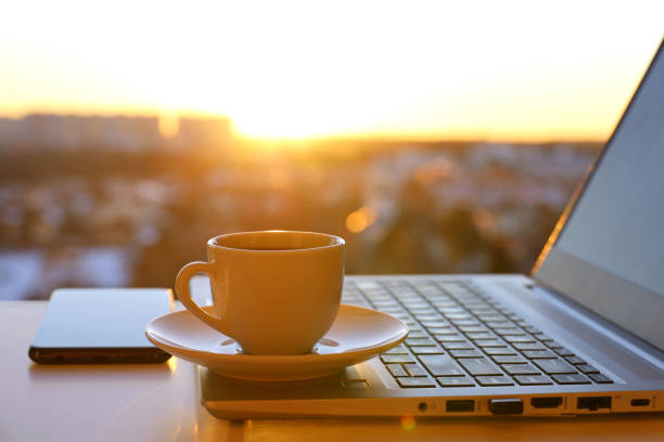istock Coffee or tea cup on laptop against the window with sunshine 1396824664