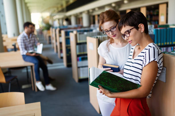 istock Students studying in library. Young success people are spending time together and learning together. 1396824907