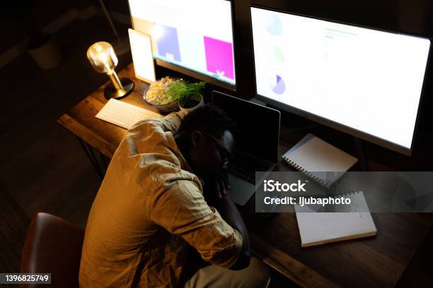 Shot of a young businessman sleeping at his desk in an office at night