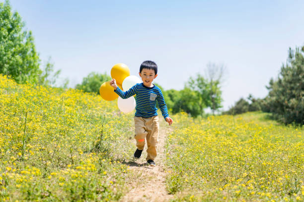 baby playing with balloons in the park stock photo