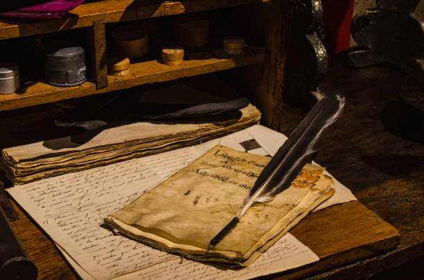 feder auf pergament auf einem antiken holztisch - manuskript stock-fotos und bilder