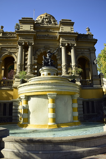 Big beautiful fountain on background of old architectural buildings and blue sky. Action. Beautiful historical fountain in landscape of old town square.