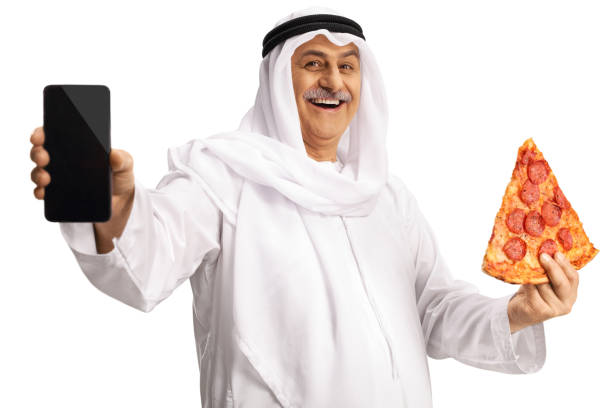 istock Arab man holding a slice of pepperoni pizza and showing a smartphone 1396830441