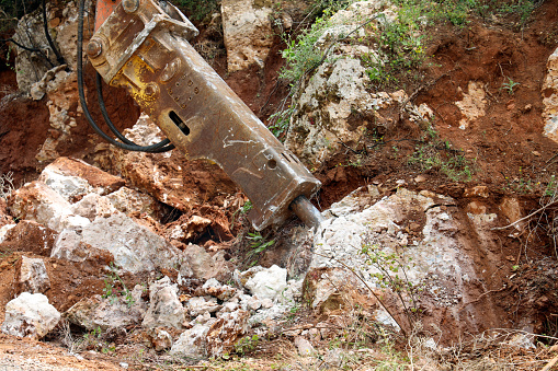 excavator crusher machine breaks rocks to widen road