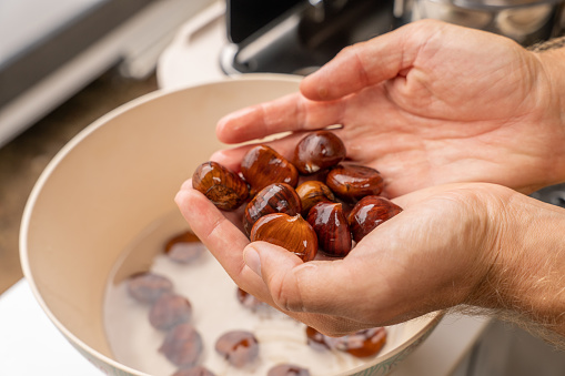 Close up on hands holding chestnuts after washing them, shining and reflecting
