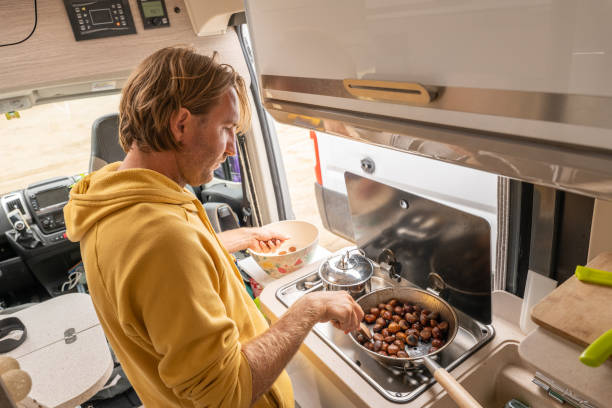 istock Living the van life, young man inside camper van cooking chestnuts 1396832877