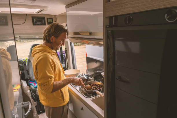 istock Living the van life, young man inside camper van cooking chestnuts 1396832930
