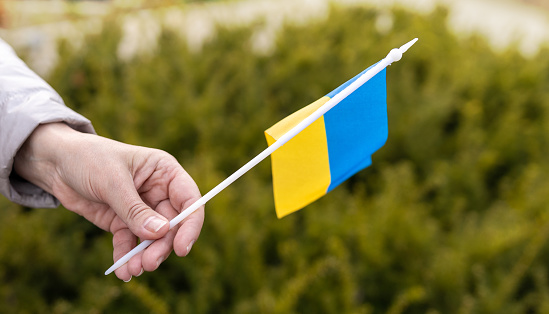 Closeup of woman hand showing flag. Woman with yellow and blue flag of Ukraine. Independence Day, Constitution day. Invasion in Ukraine