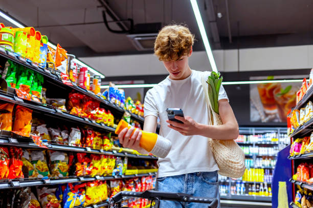 joven escaneando bebida en tienda de comestibles - tienda del vecindario fotografías e imágenes de stock