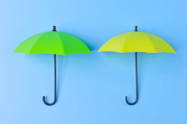 istock Green and yellow umbrella isolated on a blue background 1396836429