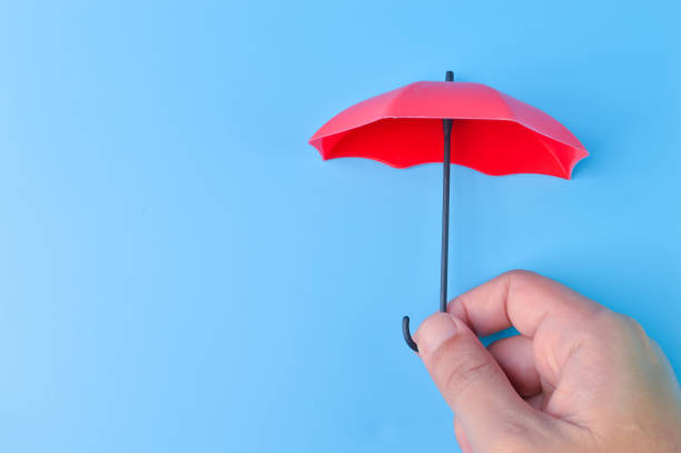 istock Hand holding red toy umbrella isolated on a blue background 1396836518