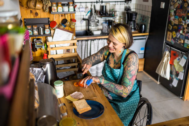 Woman in wheelchair preparing food in kitchen at home stock photo
