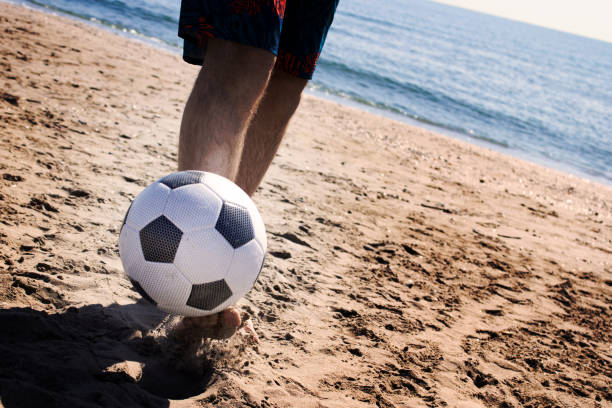 ADULT PLAYING WITH A SOCCER BALL ON THE BEACH stock photo