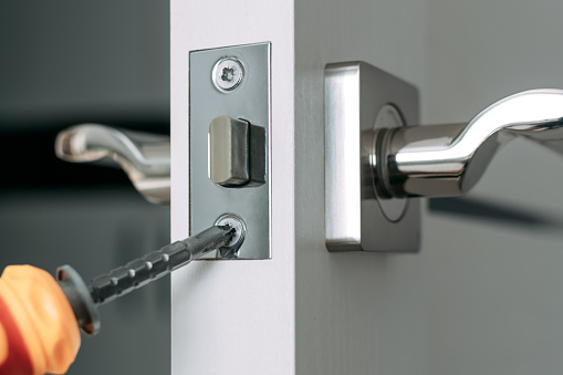 Reparar la cerradura de la puerta en la habitación con un destornillador usted mismo. Primer plano. Enfoque selectivo. photo