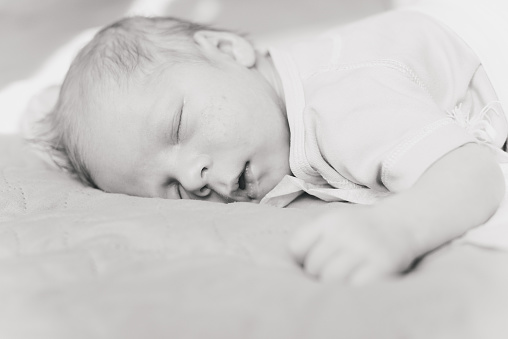 Portrait of a little newborn boy lying on the bed. Sleeping newborn baby.